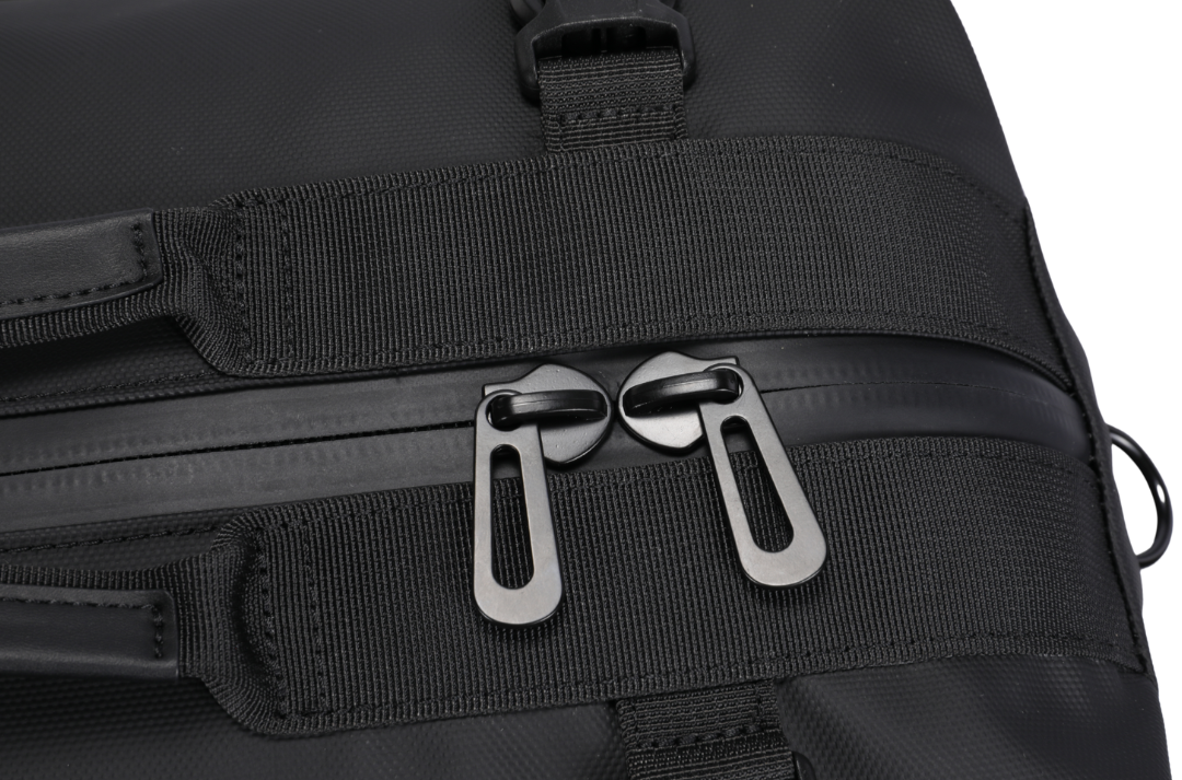 Close-up of a black bag with zippers and straps on a white background