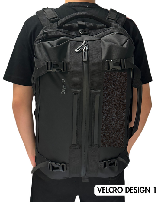 Black backpack with a velcro design on a person wearing a black shirt.