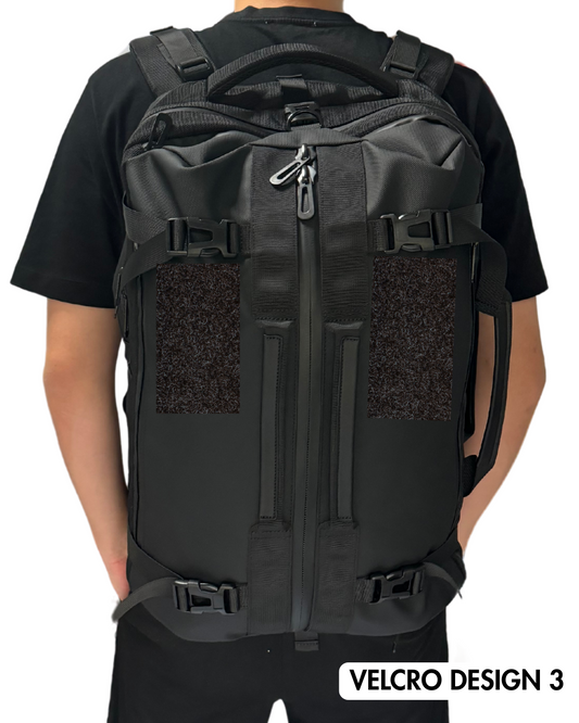 Black backpack with velcro design on a person wearing a black shirt against a white background