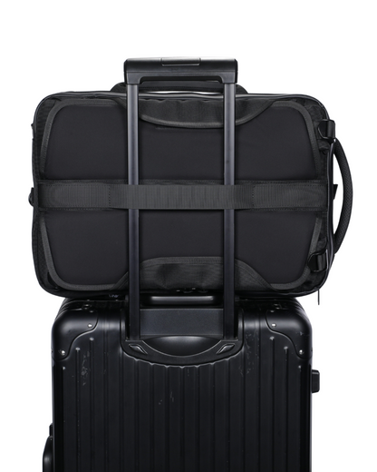 Black suitcase with a black backpack on top, featuring a shoulder strap.